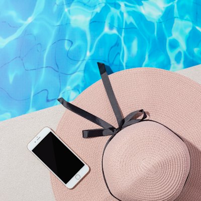 Réductions et avantages — chapeau rose et téléphone au bord de la piscine